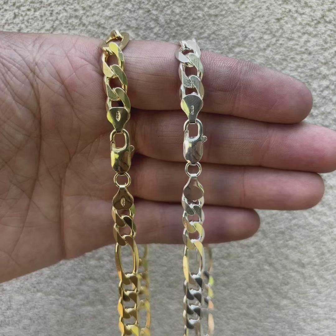Load video: Close-up video of a 925 sterling silver Figaro chain showcasing its alternating pattern of short and long flat links. The chain has a high-polish finish and reflects light as it moves, emphasizing its shine, thickness, and craftsmanship.